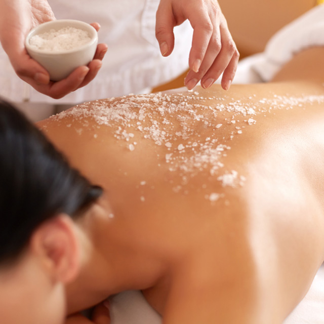 A woman getting a body scrub treatment at R Spa
